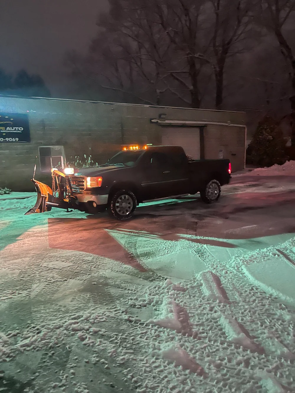 Snow plowing truck clearing commercial property during winter storm